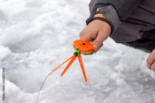 A man holds a small orange fishing pole for fishing.