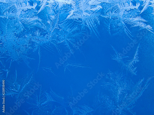 Beautiful crispy frost structure on a window with cold blue gradient light