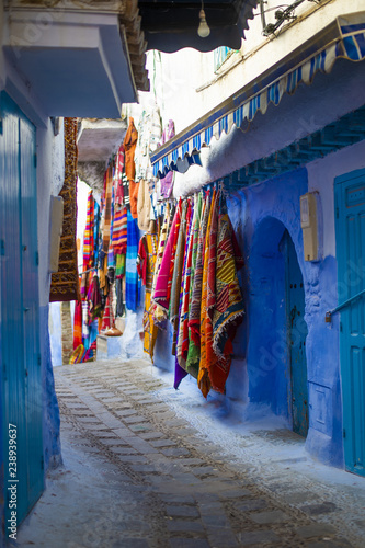 Some colorful traditional Moroccan clothes are hanging on the walls of the blue city of Chefchauen, Morocco. © Travel Wild