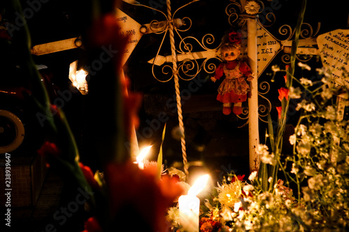 Grave Decorations with Candles, Flowers, and a Doll for Day of the Dead in Mexico City