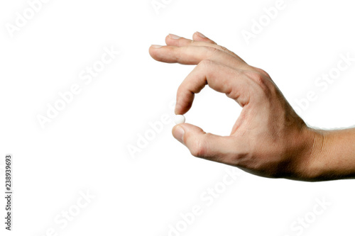 man's hand holding a white pill between thumb and forefinger. isolated on white background. copy space. decor and design. hard light.  selective focus.