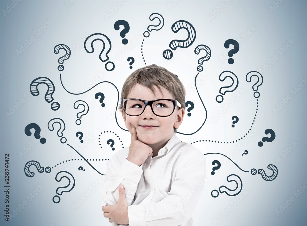 Thinking little boy, question marks on gray wall Thinking little boy, question marks on gray wall