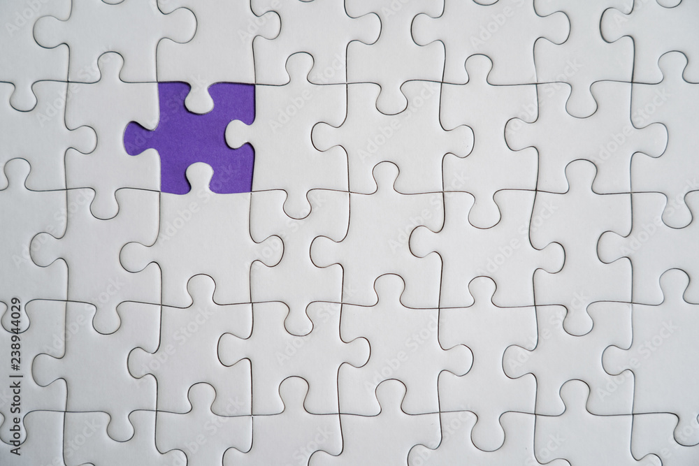 Fragment of a folded white jigsaw puzzle and a pile of uncombed puzzle elements against the background of a Violet surface. Fragment of a folded white jigsaw puzzle and a pile of uncombed puzzle elements against the background of a Violet surface.