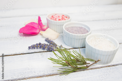 Aromas of bath salt. Rose, lavender and pine near bowls with colorful bath salt on light wooden background top view copy space