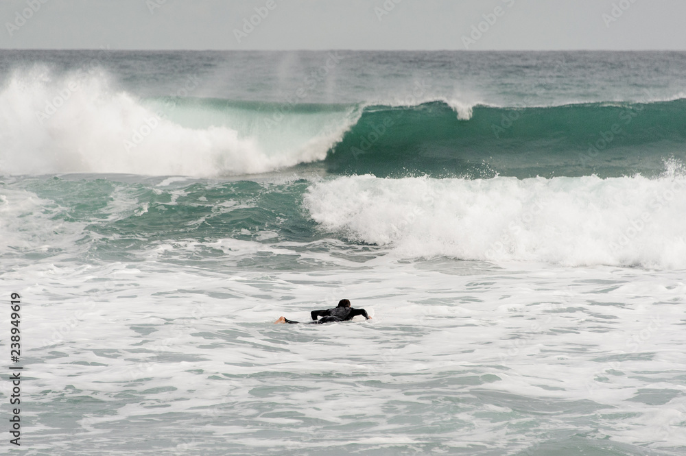 Brunette guy in the black swimsuit lying on a surf on the sea Brunette guy in the black swimsuit lying on a surf on the sea