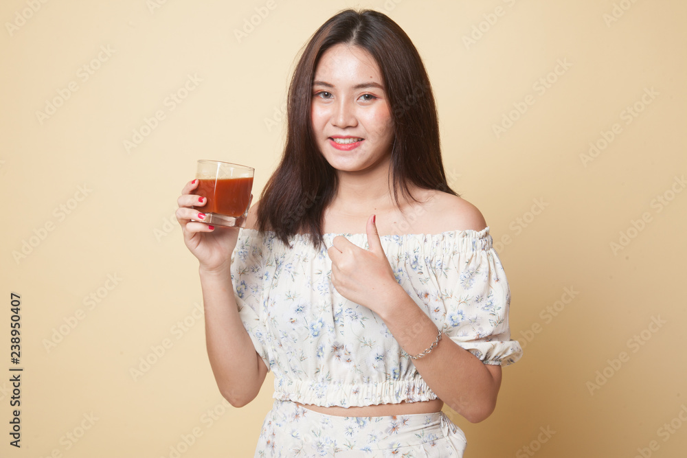 Young Asian woman thumbs up with tomato juice. Young Asian woman thumbs up with tomato juice.