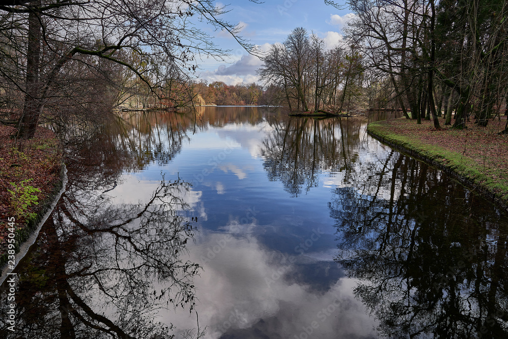 A lake in autumn with reflections of a blue sky, Badenburger See, Nyphenburg park, Munich, Germany