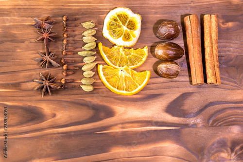 Mulled wine in rustic mug with spices and ingredients on wooden background. Top view, flat lay. Retro toned photo. Copy space for your text.