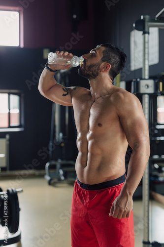 Strong man in the gym drinking water