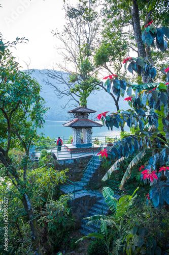 Green shore of lake Fewa, Pokhara. Small hindu temple and flowering trees.