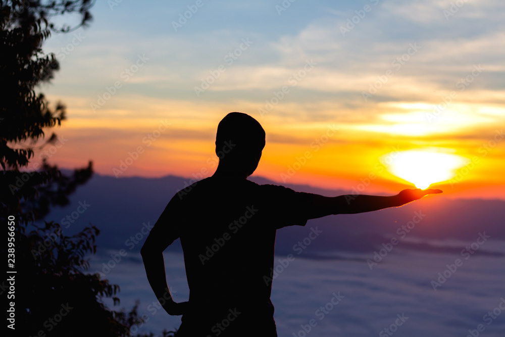 Silhouette of man hand holding sun at winter morning sunrise