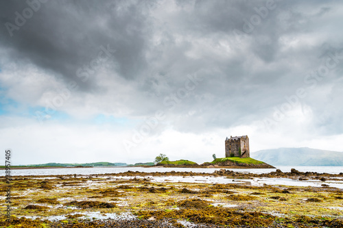 Mystical Castle Stalker on an islet on Loch Laich, cloudy day and low tide, scary and lost castle in Scotland, Great Britain photo