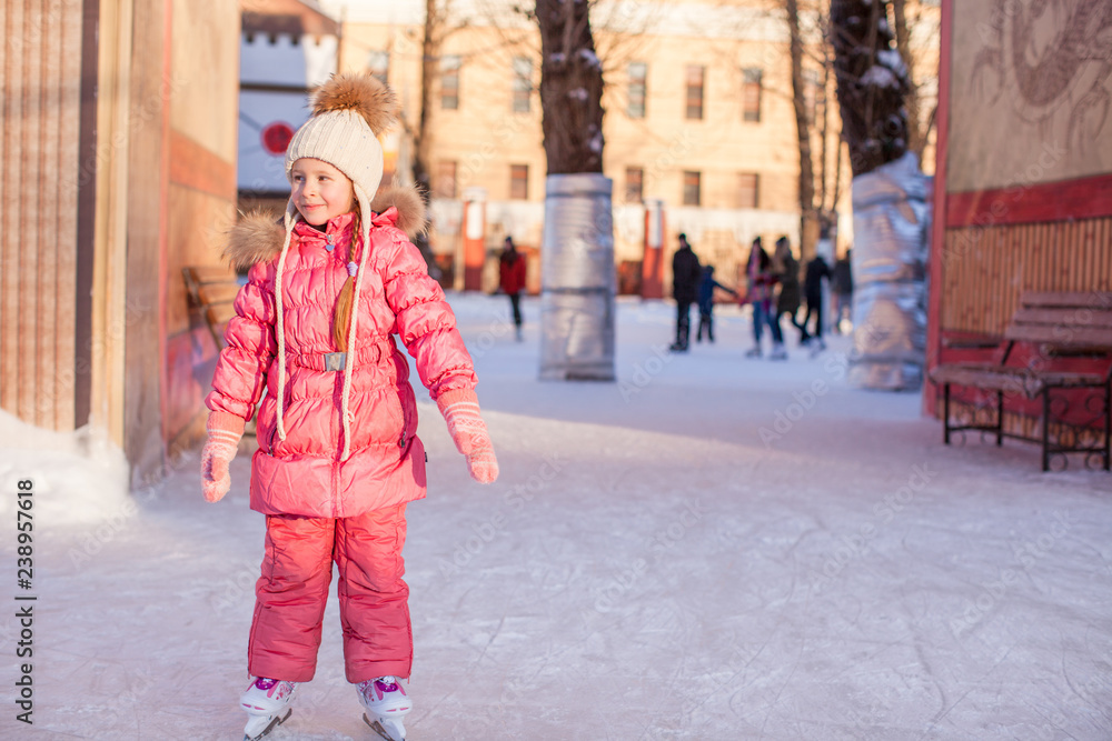 Adorable little girl enjoying skating at the ice-rink