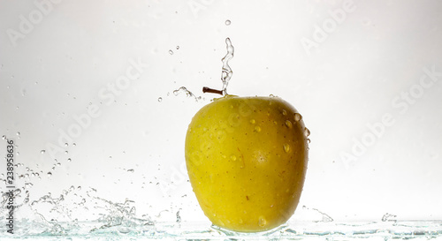 Green apple on a light background and splashing water