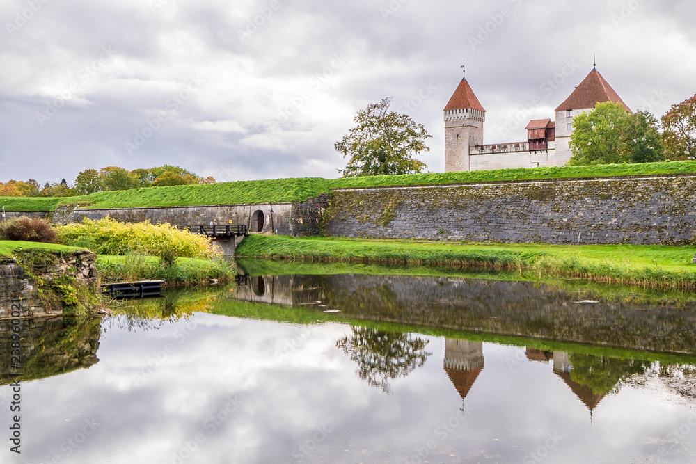 The castle and its walls are reflected in the water of the moat