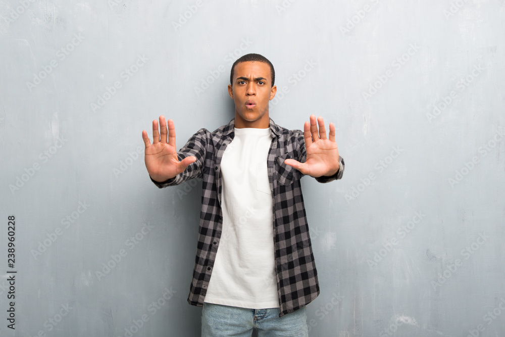 Young african american man with checkered shirt making stop gesture for disappointed with an opinion Young african american man with checkered shirt making stop gesture for disappointed with an opinion