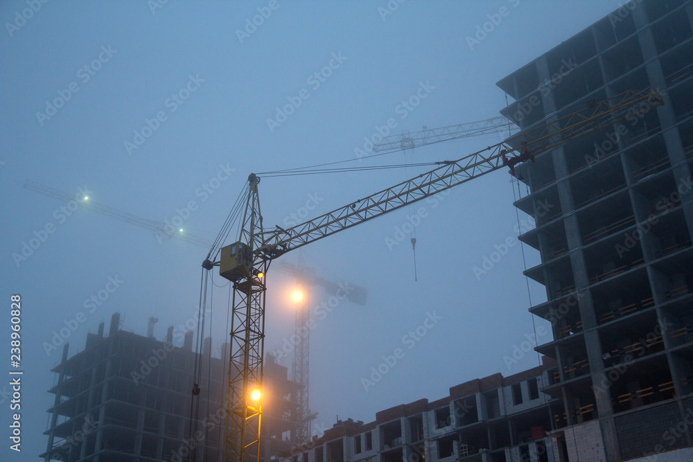 Construction cranes and new building on the background of the evening sky. Industry