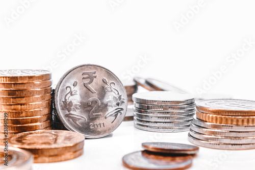 Stacks of coins and Indian rupees on a white background