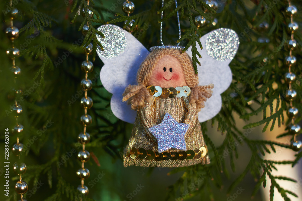 Festive decorations. Christmas angel on a tree branch. Gold beads. Handmade Christmas tree toy. Natural photo outdoors. Winter vacation. Happy New Year and Merry Christmas. Festive decorations. Christmas angel on a tree branch. Gold beads. Handmade Christmas tree toy. Natural photo outdoors. Winter vacation. Happy New Year and Merry Christmas.