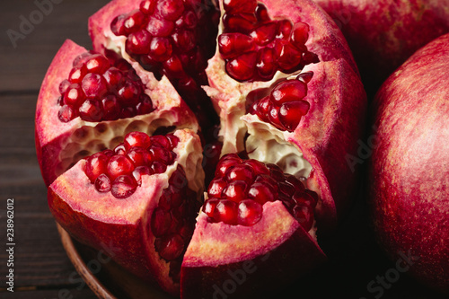 Cutted pomegranate in the plate on dark wooden background