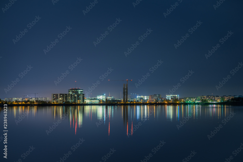 Night scene with city view and reflections in lake.
