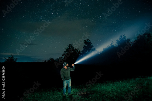 Man searching with flashlight in outdoor by night photo