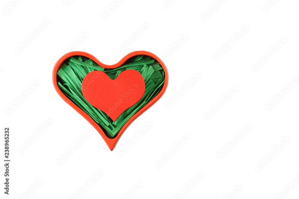 Red painted wooden heart enclosed with green paper raffia strips in red box isolated on white background Red painted wooden heart enclosed with green paper raffia strips in red box isolated on white background