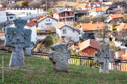 Ancient stone crosses at the churchyard of St. Petka Eastern Orthodox Church in Tsari Mali Grad fortress, the village of Belchin, Bulgaria in the background photo