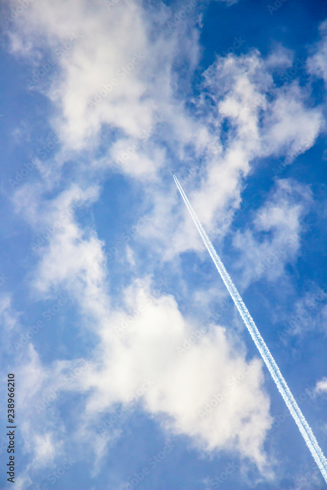 Skyscape with a plane and contrail through fluffy clouds Skyscape with a plane and contrail through fluffy clouds