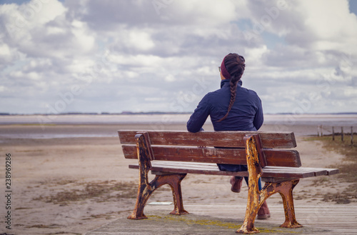 Фотография Lonely woman waiting on a bench at the beach.