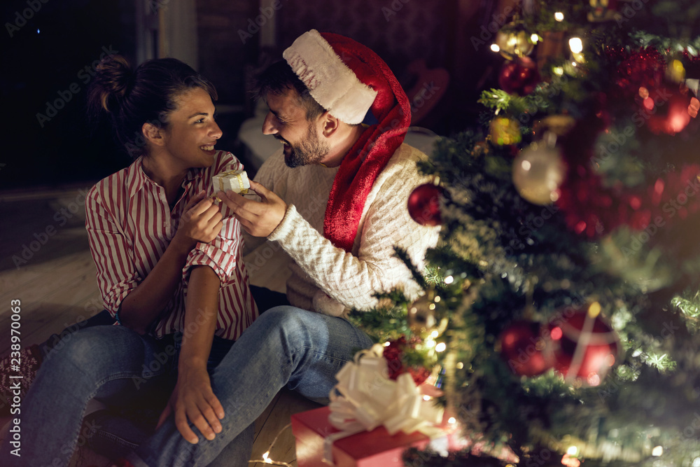 © luckybusiness - happy couple next to decorated Christmas tree, exchanging Christmas presents and having fun.. © luckybusiness - happy couple next to decorated Christmas tree, exchanging Christmas presents and having fun..