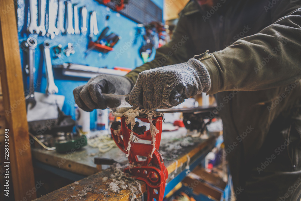 A male worker in a ski service workshop repairs the sliding surface of the skis. Close-up of a hand with a plastic scrapper for removing wax, removing new wax. Theme repair of ski curb A male worker in a ski service workshop repairs the sliding surface of the skis. Close-up of a hand with a plastic scrapper for removing wax, removing new wax. Theme repair of ski curb