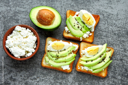 Appetizing avocado toasts with curd and egg.