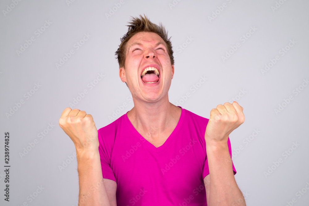 Happy young handsome man looking excited with fists raised Happy young handsome man looking excited with fists raised