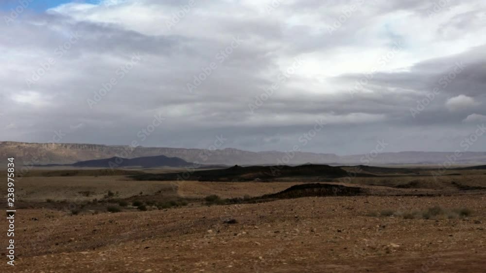 Slow motion wild landscape of Makhtesh Ramon, Ramon Crater, in the Negev desert , Israel. 4k. View from the bottom of the hollow. In the background 450-meter wall of the crater. Slow motion wild landscape of Makhtesh Ramon, Ramon Crater, in the Negev desert , Israel. 4k. View from the bottom of the hollow. In the background 450-meter wall of the crater.
