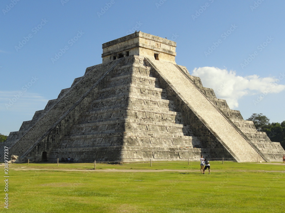 The ancient maya pyramid at the archaeological zone at Chichen Itza. Temple of Kukulcan, Mexico. Blue sky and green grass.