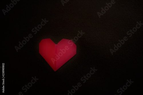 A red color origami heart on a black background