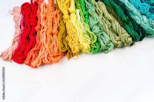 Rainbow color threads for embroidery on a white background.