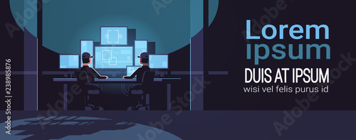 security workers watching video surveillance camera on monitor in control monitoring safety center dark guard room interior flat horizontal copy space