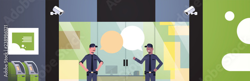 security guard men chat bubble communication at entrance door business building exterior CCTV surveillance camera equipment mix race colleagues in uniform flat horizontal