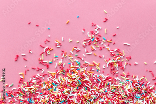 Colorful sprinkles on a pink background, top view with copy space photo