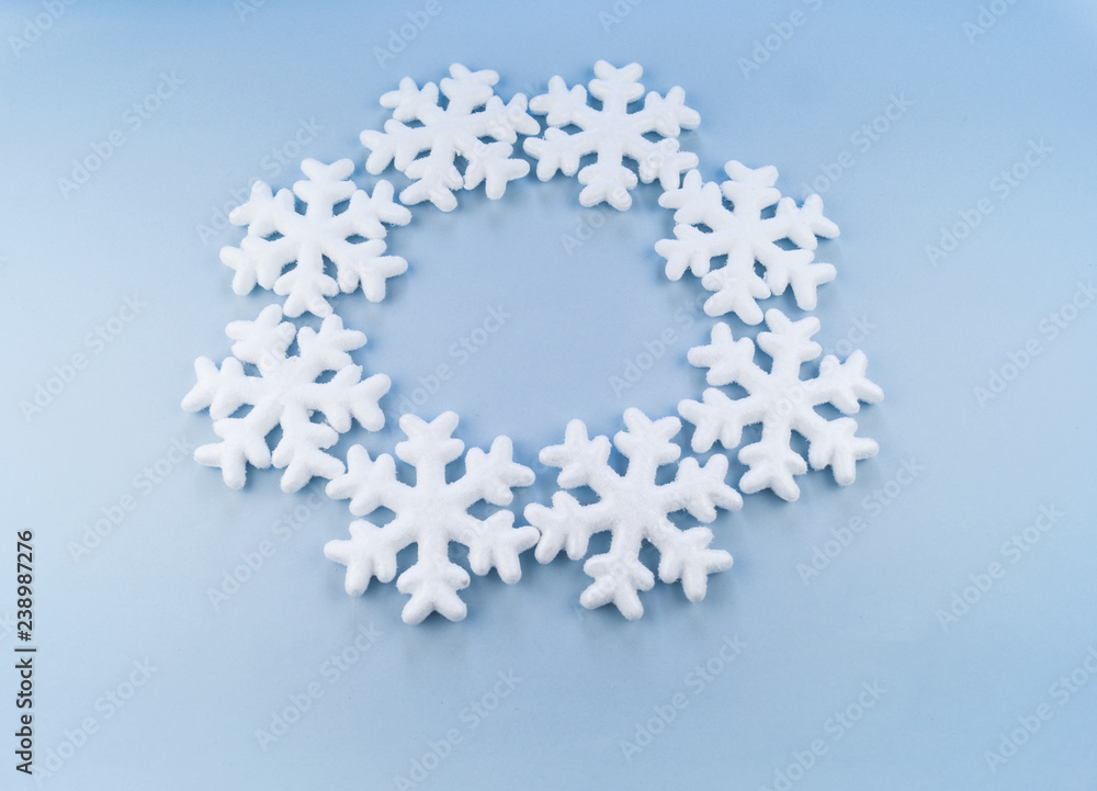 A wreath in a circle of decorative snowflakes on a blue background.