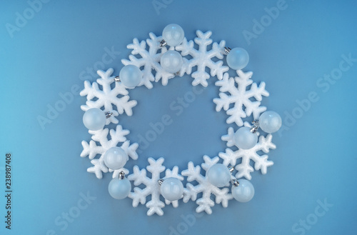 A wreath in a circle of decorative snowflakes on a blue background.