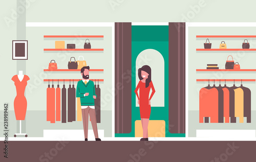 man seller consultant near woman trying on new dress elegant woman looking at mirror fashion shop female clothes market modern shopping mall interior flat horizontal
