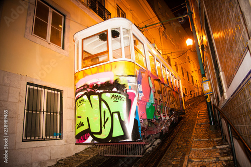 Old traditional tour tram on a old narrow street of Alfama district by night in Lisbon. Portugal.