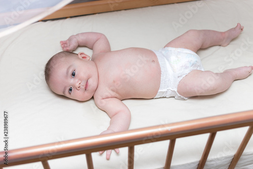 infant boy is lying in a baby crib