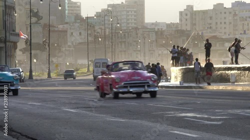 old classic american cars driving on famous waterfront malecon promenade, waves splash on cuban fishermen, Old Havana, Cuba