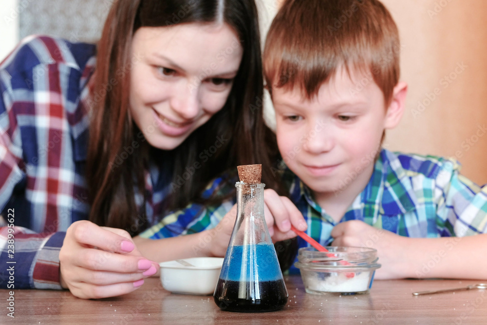 Chemistry experiments at home. Mom and son make a chemical reaction with the release of gas in the flask. Chemistry experiments at home. Mom and son make a chemical reaction with the release of gas in the flask.