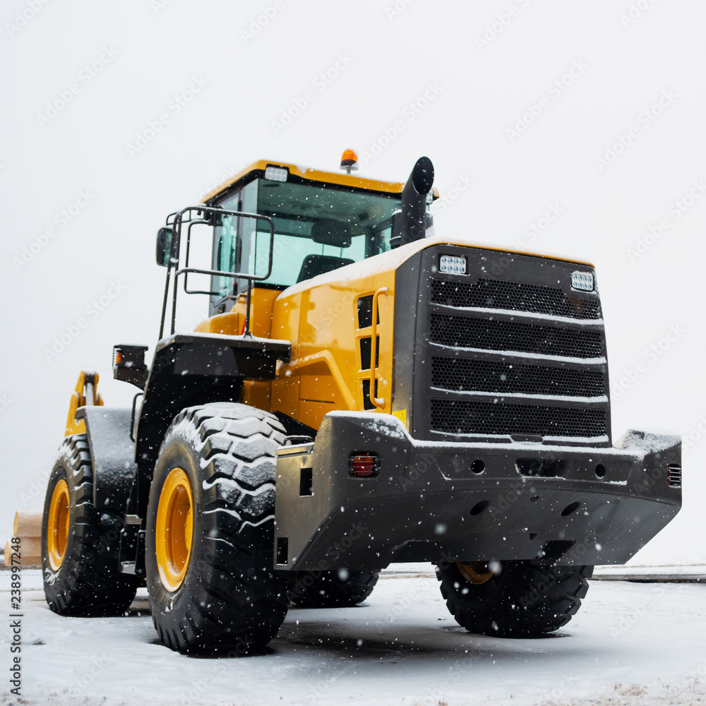 Yellow wheel front loader. Construction and handling equipment. Heavy diesel tractor, construction machinery, industrial vehicle. Winter time