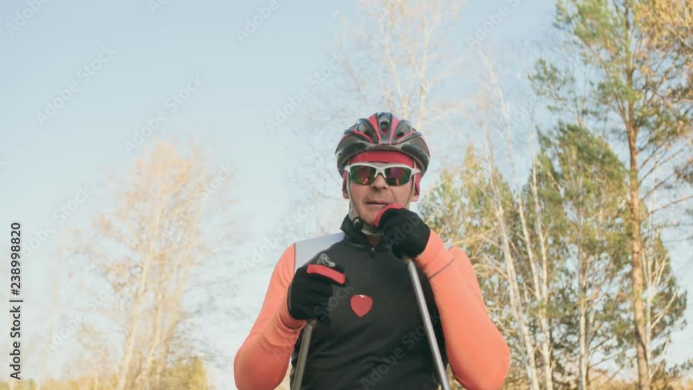 Training an athlete on the roller skaters. Biathlon ride on the roller skis with ski poles, in the helmet. Autumn workout. Roller sport. Adult man riding on skates. Shooting an athlete in motion Training an athlete on the roller skaters. Biathlon ride on the roller skis with ski poles, in the helmet. Autumn workout. Roller sport. Adult man riding on skates. Shooting an athlete in motion
